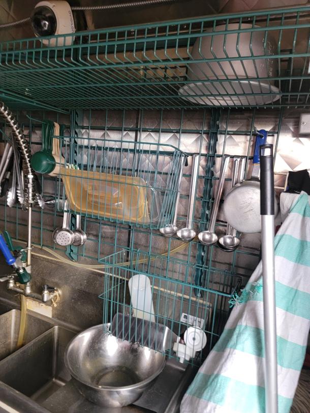 2021 Quality 16’ mobile kitchen interior with sink, shelving, and utensils. Features a diamond-plate wall and security camera.