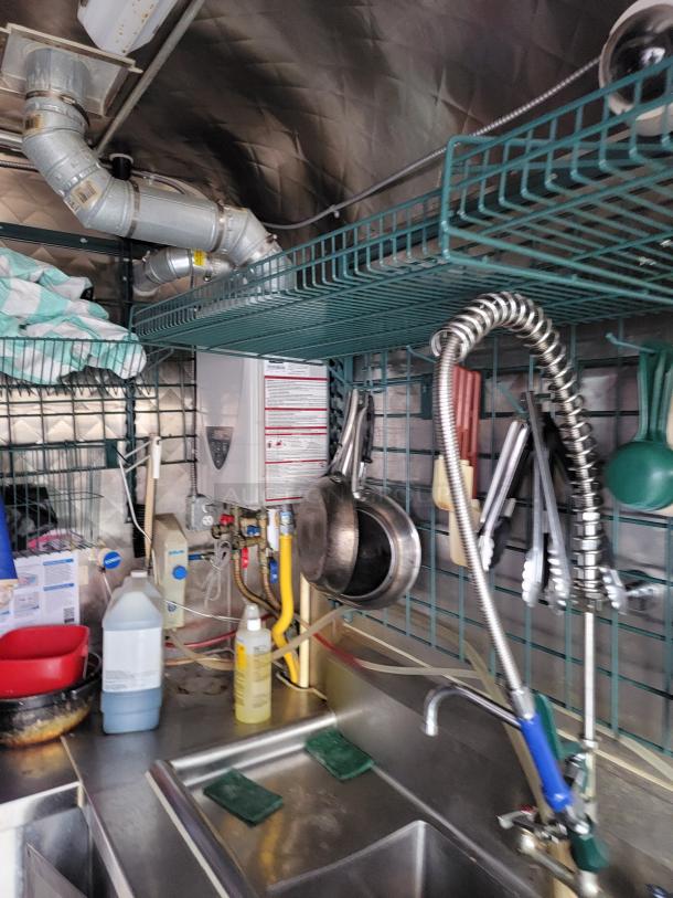 2021 Quality 16' mobile kitchen trailer interior with triple sink, spray faucet, and storage rack.