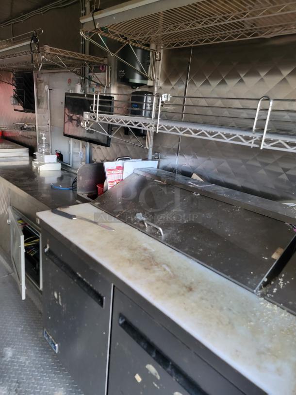 2021 Quality 16' mobile kitchen interior with Arctic Air units, stainless steel counters, diamond-plate flooring, and shelving.