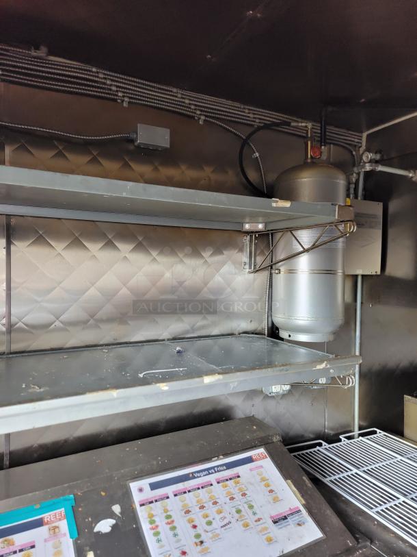 2021 16' REEF/NBRHD mobile kitchen trailer interior showing stainless shelving, menu boards, and utilities.
