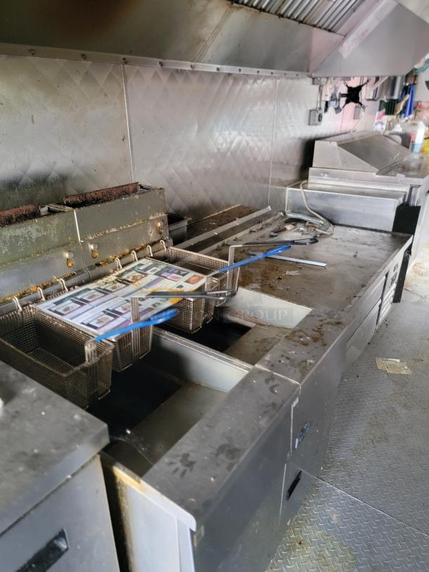 2021 16' Quality mobile kitchen trailer interior with heavy-duty exhaust hood, dual deep fryer, and large flat-top griddle.