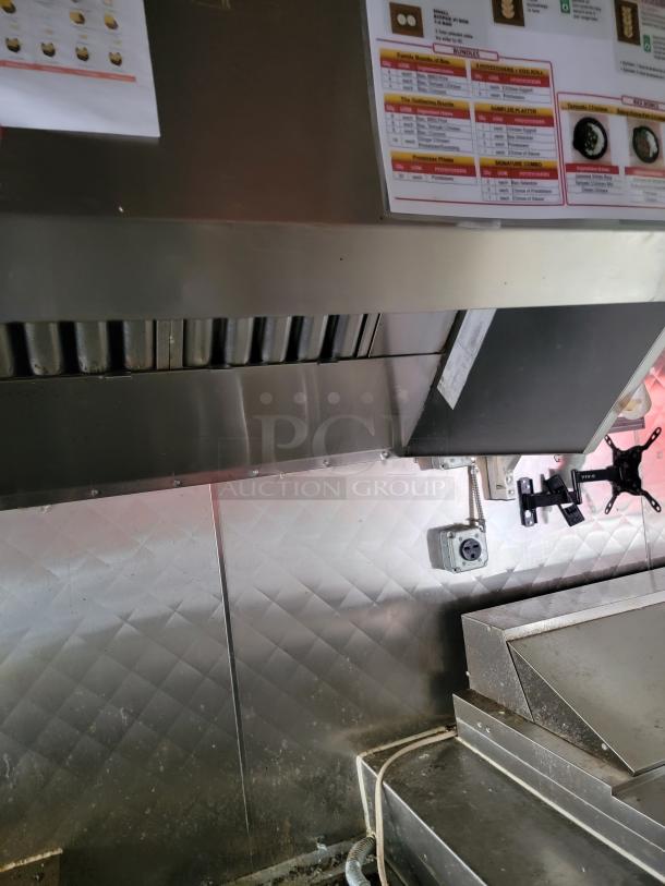 Inside view of a 2021 16' Quality mobile kitchen trailer showing a commercial exhaust hood, griddle, and diamond-plate wall.