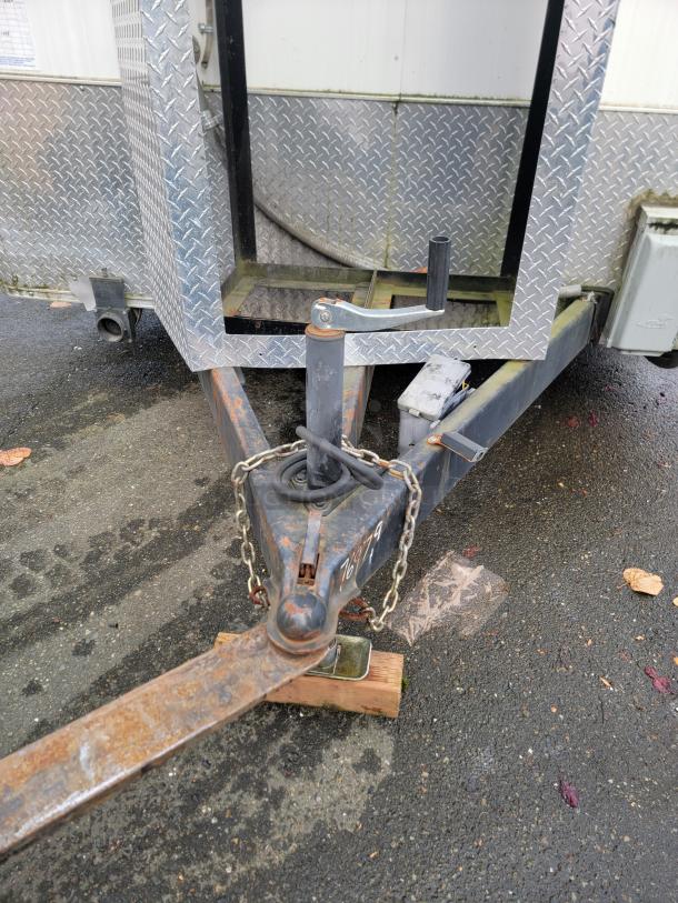2019 Diamond Cargo 16' food trailer hitch, showing rust and chain. Diamond plating detail. Ready for towing.