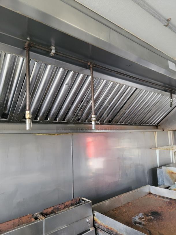 Interior of 2019 Diamond Cargo food trailer showing commercial exhaust hood, Pitco Deep Fryer, and Wells Griddle/Range.