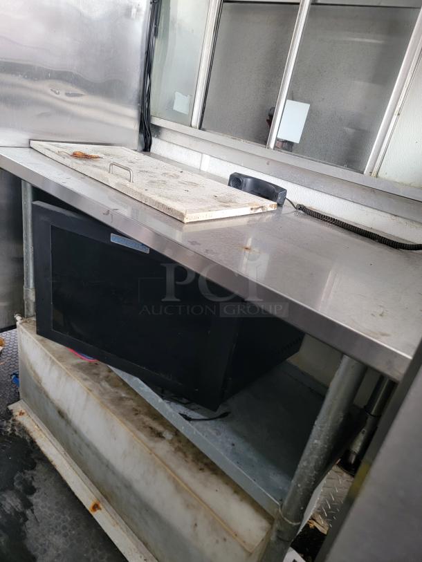 Interior view of a 2019 Diamond Cargo 16' food trailer. Features stainless steel prep surfaces and a storage area below.