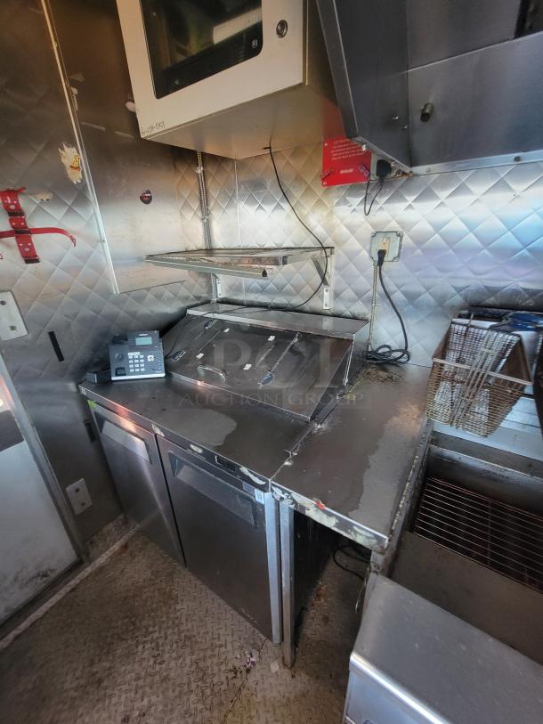 2020 16' Quality mobile kitchen trailer interior showing stainless steel walls, diamond-plate flooring, Turbo air refrigeration, and cooking equipment.