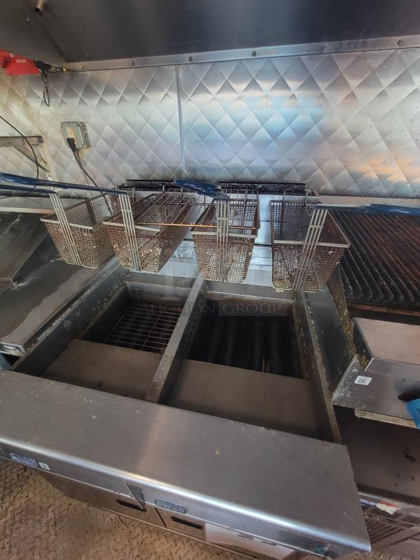 Mobile kitchen interior featuring Pitco gas fryer, griddle, stainless steel walls, and diamond-plate flooring.