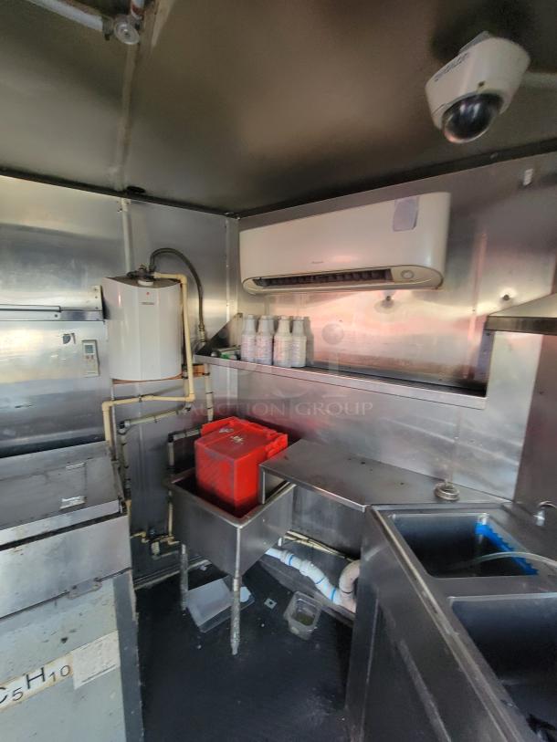 Interior view of a 2019 Quality 24' food trailer featuring stainless steel sink setup, gas connections, and mounted appliances.