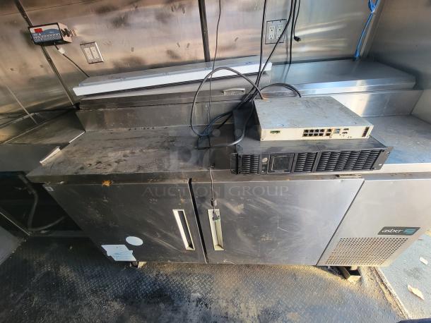 2019 Quality 24' food trailer interior showing Asber under-counter unit, prep surface, and electrical setup. Slight wear visible.