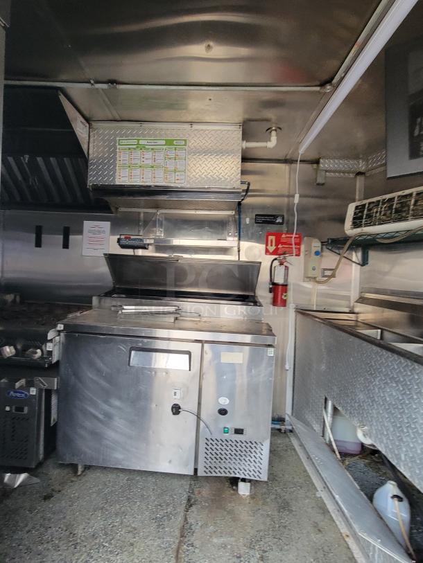 2019 Quality 24' food trailer interior with stainless steel kitchen, Royal griddle/range, Pitco fryer, AC unit, and ventilation hood.
