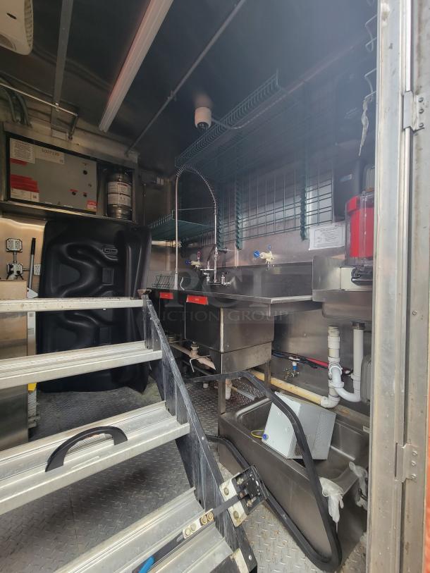 2021 28' Wendy's Mobile Ghost Kitchen interior with commercial sink, stainless steel counters, wiring, and shelving units.