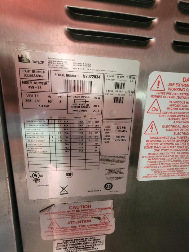 Label on a commercial appliance showing specifications for Taylor model 359-33, serial number N2022034. Includes voltage details, amperage, and caution instructions.