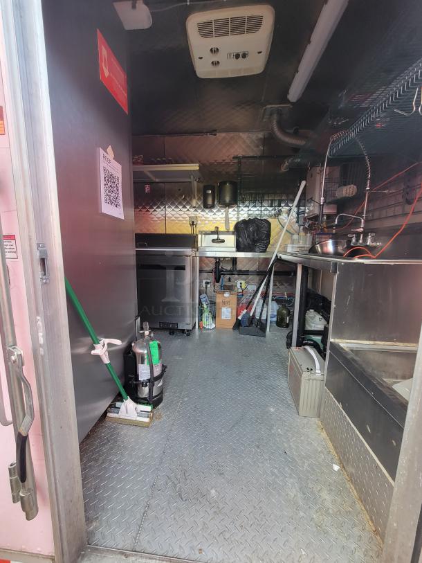 2021 24' Quality Kitchens mobile food trailer interior, featuring stainless steel surfaces, storage, and sanitation station.
