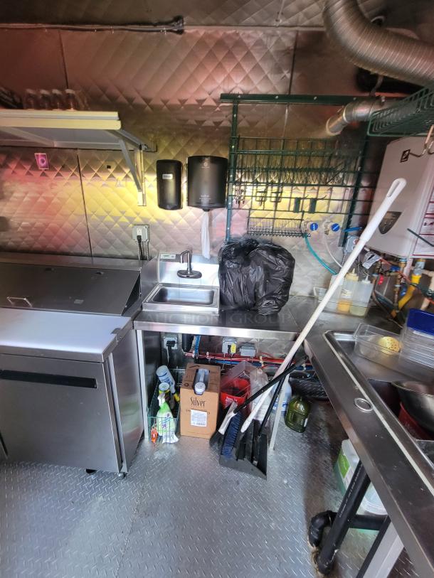 2021 Quality Kitchens 24' mobile food trailer interior, showcasing stainless steel sinks, shelving, and refrigeration units.