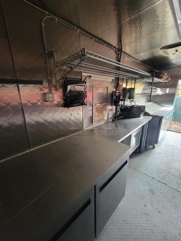 2021 Quality Kitchens 24' mobile food trailer interior with stainless steel counters, Arctic Air refrigeration, and shelving units.
