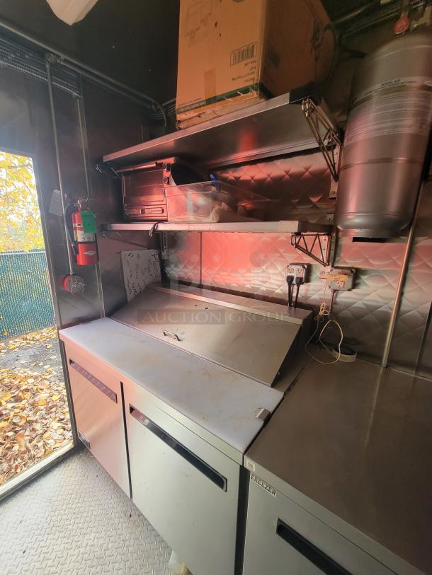 2021 24' Quality Kitchens mobile food trailer interior, showing stainless steel prep area, storage, and refrigeration units.