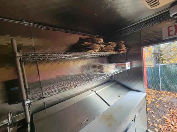 Interior of a 2021 Quality Kitchens 24' mobile food trailer with shelving, stainless steel counter, and exterior view.