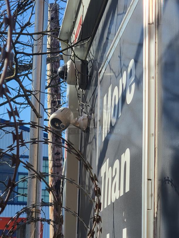 Exterior of a 2021 Quality 24' food trailer with security cameras and barbed wire, showcasing its surveillance system.