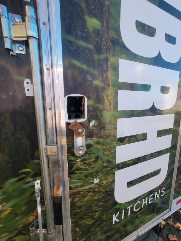 2021 24' Quality food trailer exterior with visible latch and hinge detail; rusty spots noted, "Kitchens" logo partly seen.