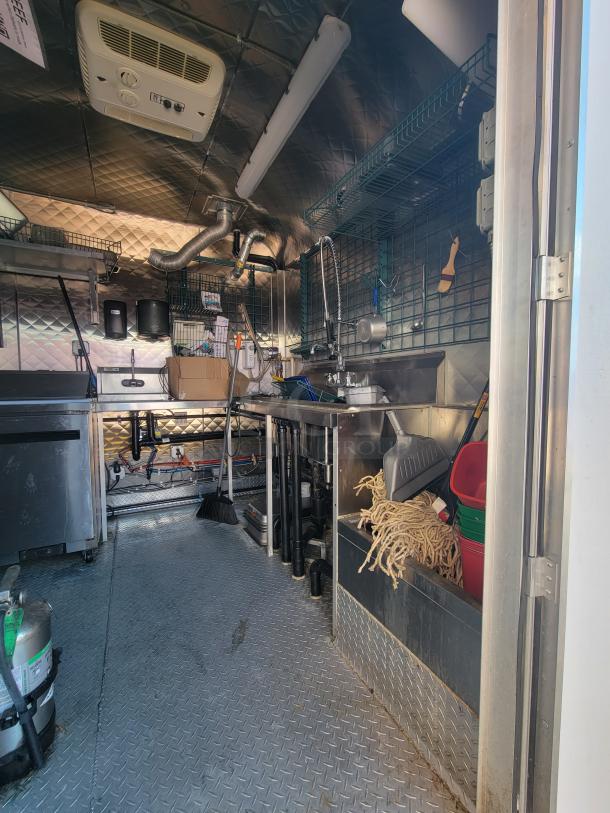 2021 24' Quality Food Trailer interior showing stainless steel build-out, plumbing fixtures, and storage, fully equipped for mobile kitchen.