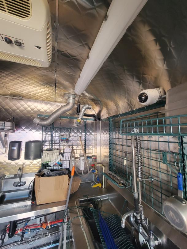 2021 24' Quality Food Trailer interior with stainless steel build, sinks, and surveillance camera. Fully equipped kitchen.