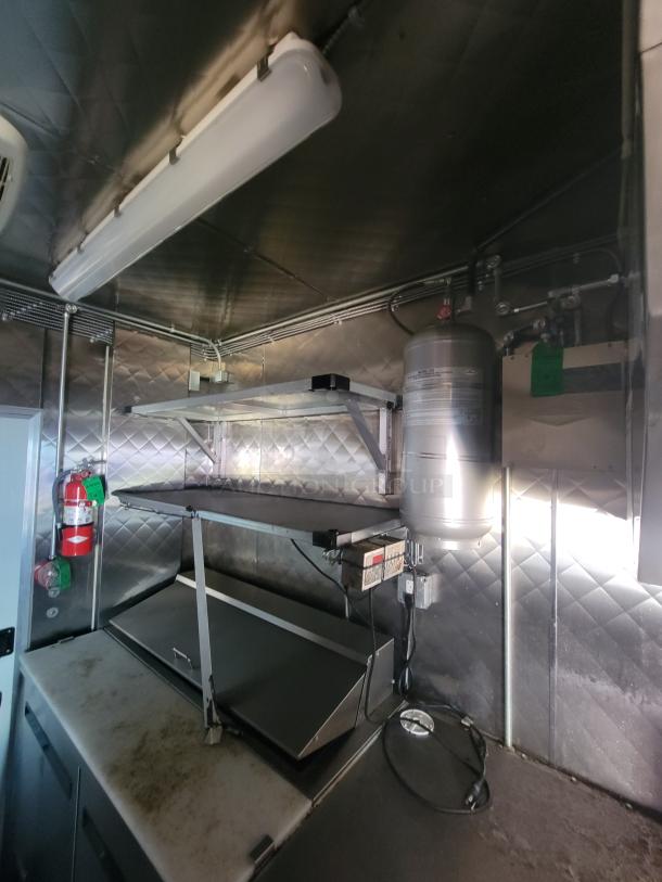 2021 Quality 24' food trailer interior, showing stainless steel build, commercial exhaust hood, griddle, fire suppression system.