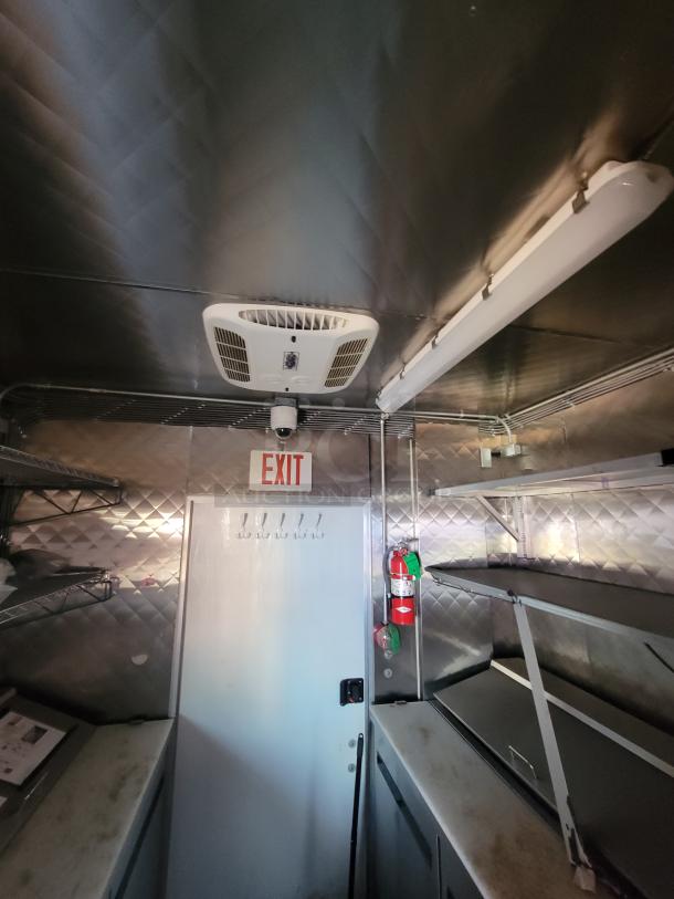 Interior of 2021 Quality 24' food trailer featuring stainless steel surfaces, climate control, exit sign, and fire extinguisher.