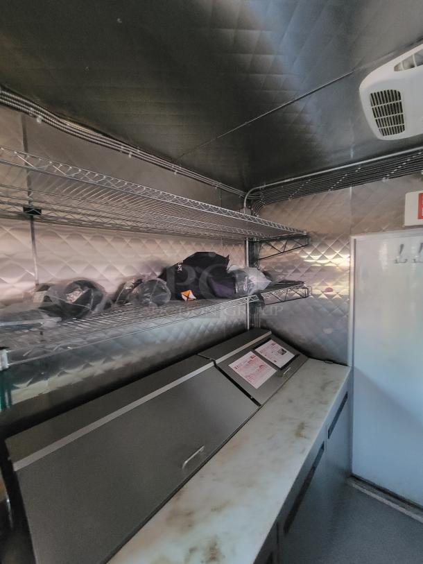 Interior of a 2021 Quality 24' food trailer, showcasing stainless steel shelving and a marble countertop.