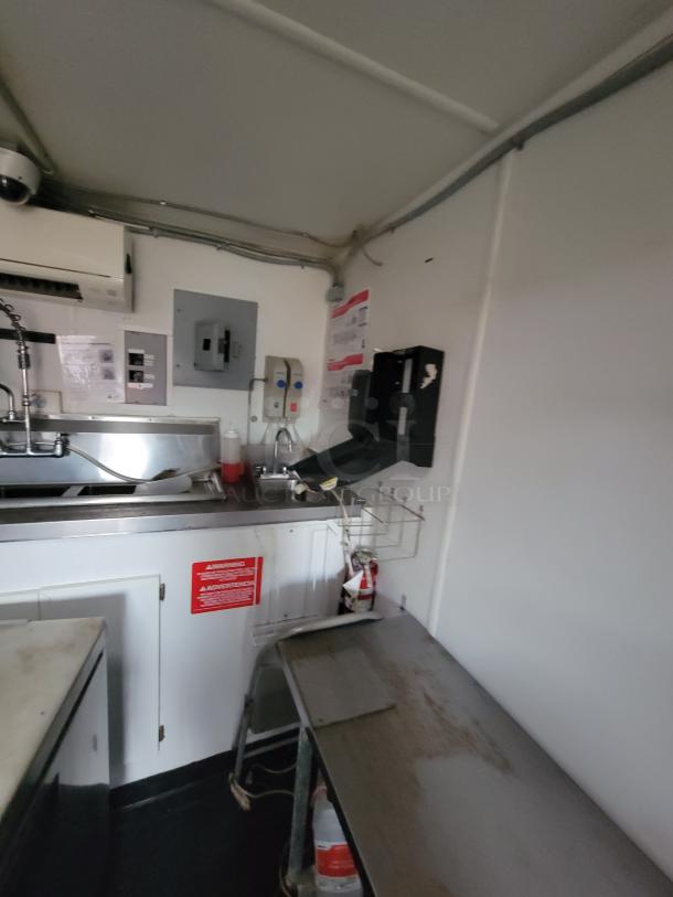 Interior of a 2020 Rock Solid mobile ghost kitchen trailer with a stainless steel 3-compartment sink, hand wash station, and fire extinguisher.