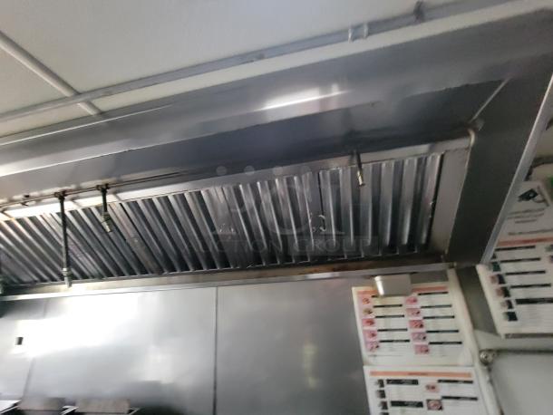 Interior view of a 2020 Rock Solid 16' mobile trailer kitchen with a steel commercial exhaust hood and visible menu displays.