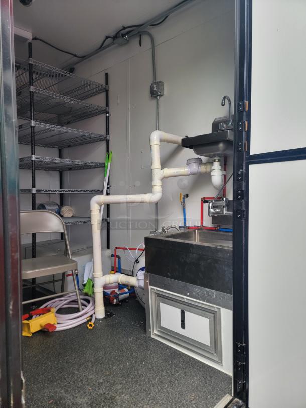 Interior of 2021 SDG 24' refrigerated trailer with chrome shelving, stainless steel sink, plumbing, and stored equipment.
