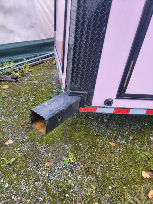 SDG 20 trailer corner detail, featuring pink exterior and black diamond plate trim. Exterior condition appears intact.