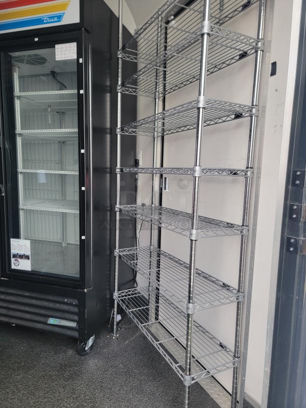 Mobile retail/freezer trailer interior showing chrome wire shelving and a commercial-grade refrigerator, ideal for food service.