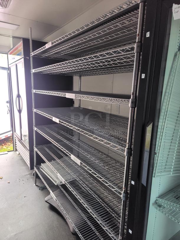 Commercial-grade mobile retail/freezer trailer interior, featuring full-length chrome wire shelving and a glass door refrigeration unit, ideal for frozen goods.