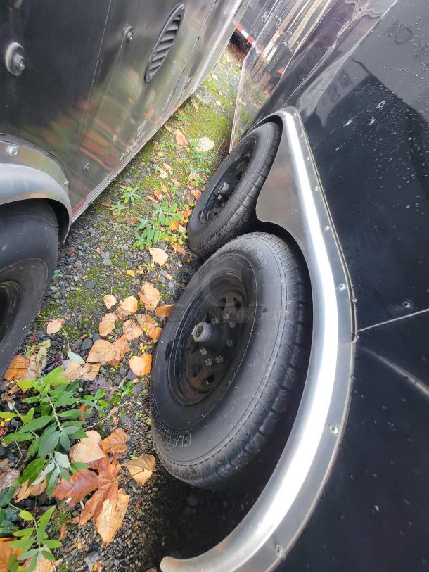 Side view of a 2021 Diamond Cargo Mobile Commercial Trailer, showing exterior wheels and black body. Some outdoor wear visible.