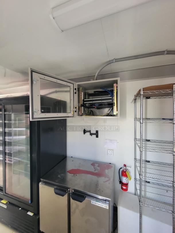 Interior view of the 2021 Diamond Cargo 24' mobile trailer with Beverage-Air refrigeration units, open electrical panel, wire shelving, and a fire extinguisher.