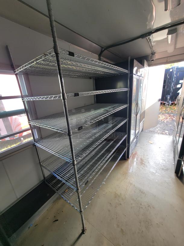 Interior of a 2021 Diamond Cargo 24' mobile trailer featuring metal shelving and a large glass-door refrigerator for food service.