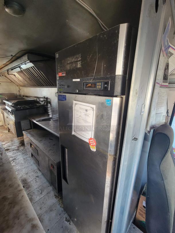 2007 Utilimaster Pro-Kitchen Food Truck interior, showing industrial fridge, stovetop, and ventilation. Some signs of wear.