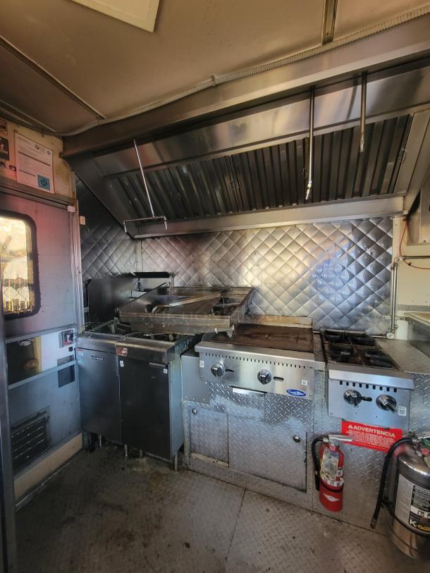2018 STM 14-Foot Concession Trailer interior with commercial appliances. Includes grill, burners, and hood. Ready for use.