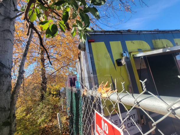 2018 STM 14-Foot Concession Trailer parked near trees. Yellow and black exterior, partial view through fence. "No Trespassing" sign visible.