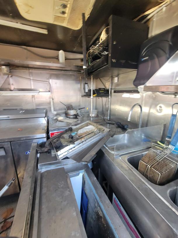 2019 Anvil 16' food trailer interior, showing severe fire/smoke damage, grease build-up, and disarray. Sold for restoration.