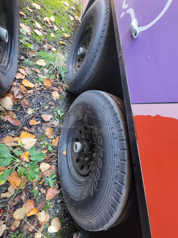 Dual axle wheels of a 2021 SDG 20' turnkey mobile retail trailer with a distinctive pink wrap and road-ready tires.