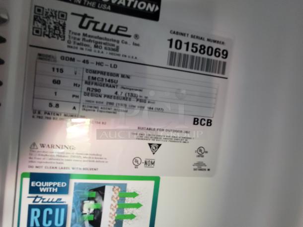 Tag on True Manufacturing cooler with model QDM-45-HC-LD, serial number 10158069, and details about compressor, refrigerant, and design pressure.