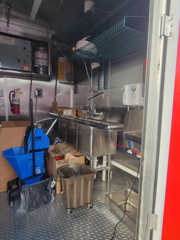 2022 Rock Solid Cargo 28' ghost kitchen trailer interior with stainless steel sink, cleaning supplies, and storage racks.