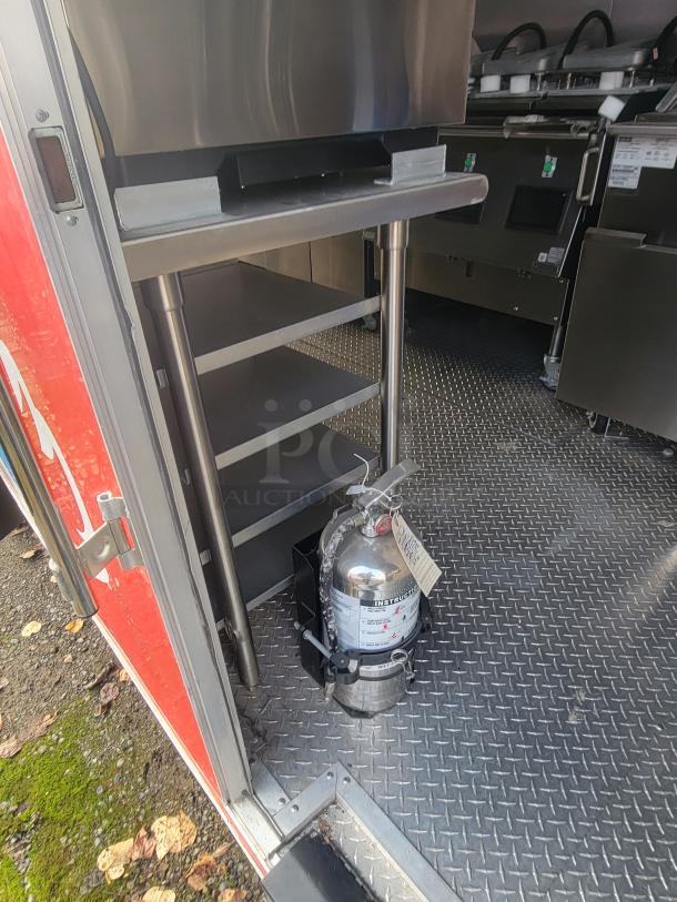 Rock Solid Cargo 28' ghost kitchen trailer interior with shelving and fire extinguisher, featuring diamond plate flooring.