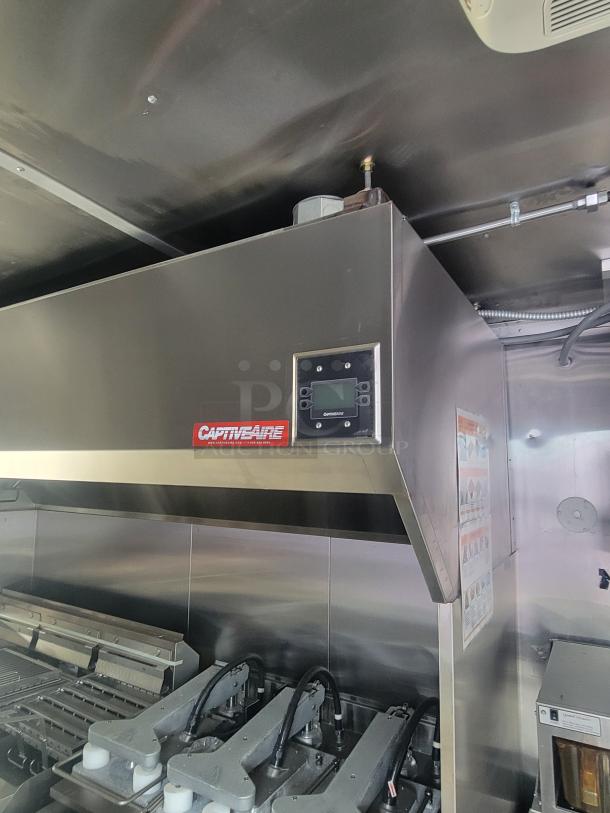 Interior of a 2022 Rock Solid Cargo ghost kitchen trailer, featuring a CaptiveAire hood, stainless steel finish, and new cooking equipment.