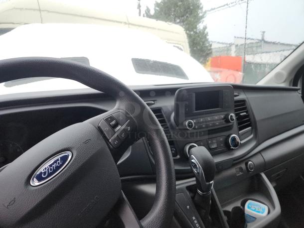 Interior view of a 2020 Ford Transit-350 High Roof Extended Cargo Van. Features steering wheel controls, center console, and dashboard with infotainment system.