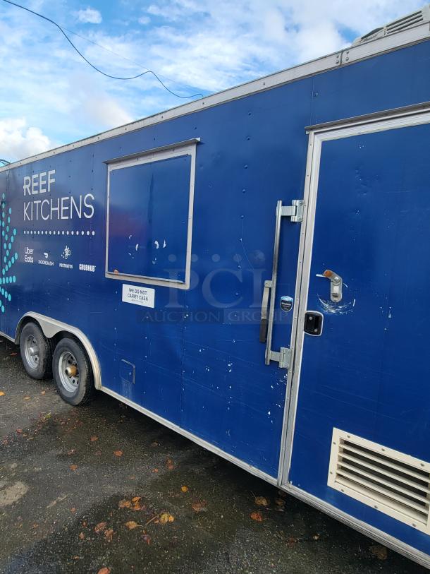 Quality Cargo Model 24 food trailer, blue with "REEF Kitchens" branding, visible wear, dual axles, exterior vent.