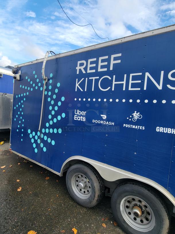 Quality Cargo Model 24 trailer, blue with "REEF KITCHENS" branding, partner logos, dual axle, in fair condition.