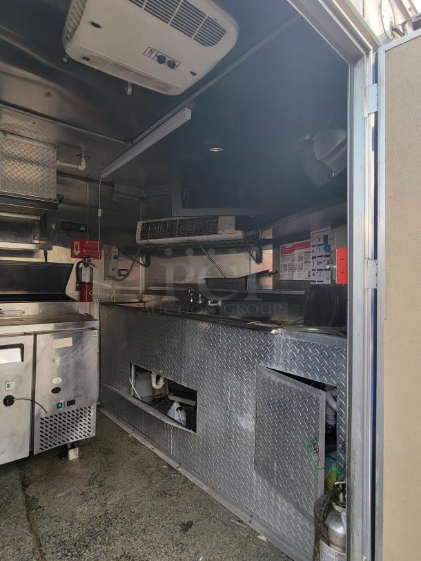 Quality Cargo Model 24 kitchen interior, diamond plate finish, with appliances and storage, showing fair used condition.